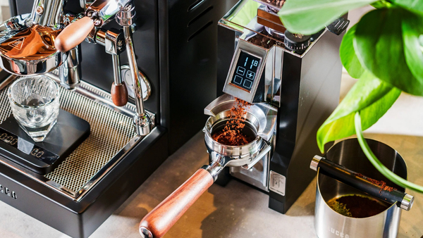 coffee grinder grinding coffee next to a black espresso machine