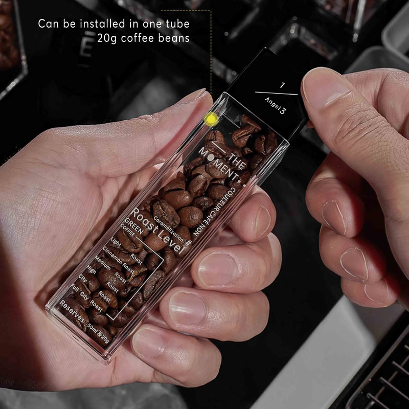 Hand holding a transparent container with coffee beans and text on a blurred background