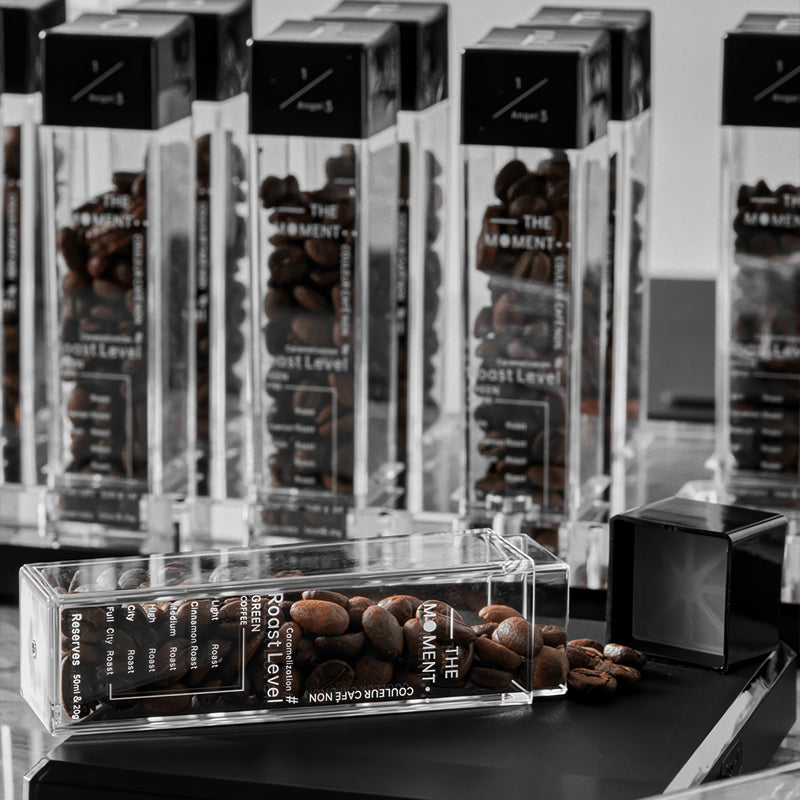 Collection of coffee packaging with 'The Moment' branding on a dark surface.
