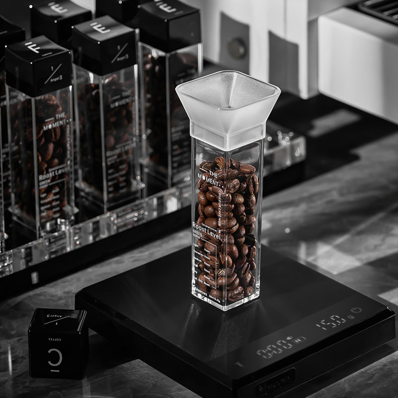 Glass container with coffee beans on a digital scale with branded boxes in the background