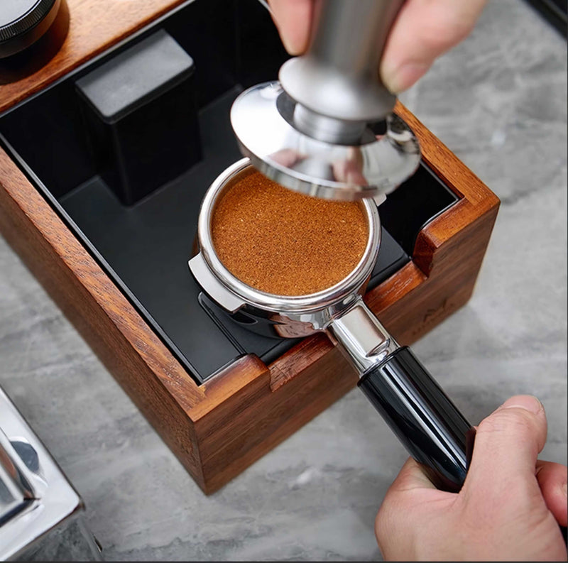 Person using a coffee tamper to compress coffee grounds in a portafilter.