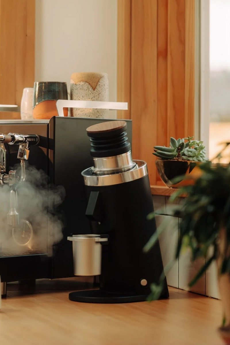 Black coffee grinder with steam coming out in a kitchen setting